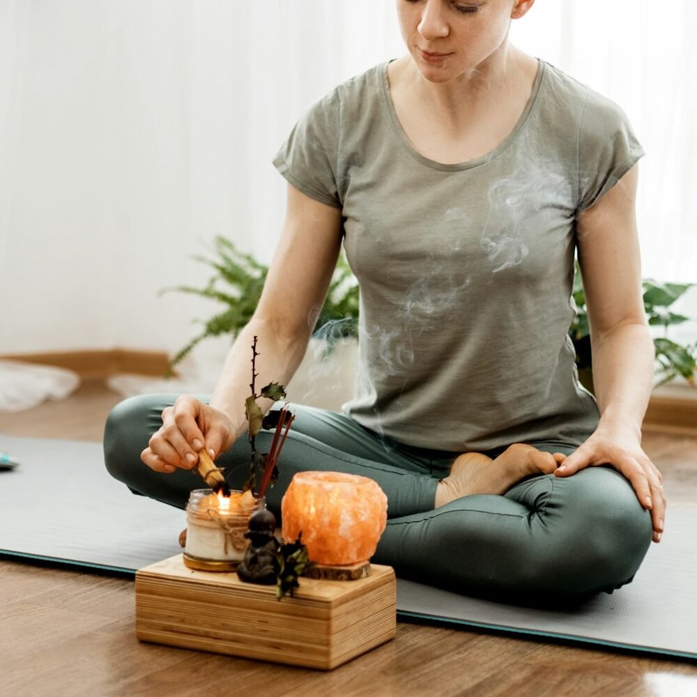 Young relaxed woman doing yoga at home with candles and incense